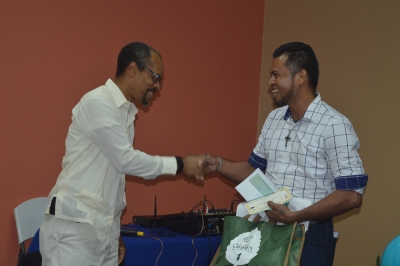 CRFM Executive Director, Milton Haughton, presents checque to Govany Flores, son of the 2018 Fisher of the Year, David Flores.